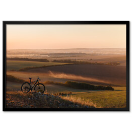 Plakat w ramie Sylwetka roweru na wzgórzach w trakcie zmierzchu
