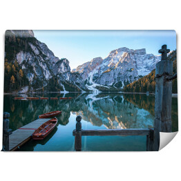Fototapeta Idylliczne górskie jezioro z pomostem i łodziami przed malowniczym skalistym krajobrazem