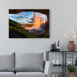Obraz na płótnie Wodospad oświetlony promieniami słonecznymi, widok z jaskini, Islandia