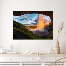 Plakat samoprzylepny Wodospad oświetlony promieniami słonecznymi, widok z jaskini, Islandia