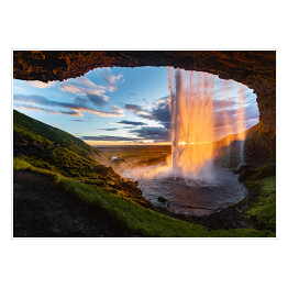 Wodospad oświetlony promieniami słonecznymi, widok z jaskini, Islandia