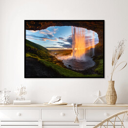 Plakat w ramie Wodospad oświetlony promieniami słonecznymi, widok z jaskini, Islandia