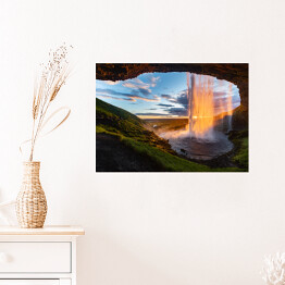 Plakat samoprzylepny Wodospad oświetlony promieniami słonecznymi, widok z jaskini, Islandia