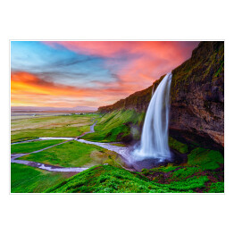 Plakat samoprzylepny Piękny krajobraz z zielonymi równinami i wysokim wodospadem wylewającym się z pokrytej mchem kamiennej ściany