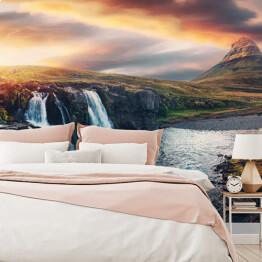 Fototapeta Niesamowity krajobraz górski z kolorowym żywym zachodem słońca na pochmurnym niebie nad słynnym wodospadem Kirkjufellsfoss i górą Kirkjufell. Islandia. popularna lokalizacja dla fotografów krajobrazowych.