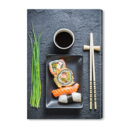 Świeże sushi, ciemna ceramika i pałeczki do jedzenia