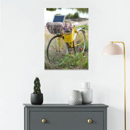 Plakat Bicykl z koszem z kwiatami na łące podczas zmierzchu