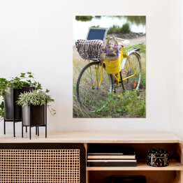 Plakat Bicykl z koszem z kwiatami na łące podczas zmierzchu
