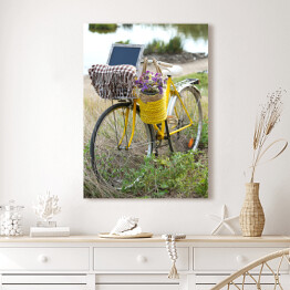 Obraz na płótnie Bicykl z koszem z kwiatami na łące podczas zmierzchu