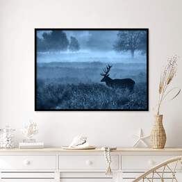 Plakat w ramie Krajobraz z jeleniem na polanie we mgle o zmierzchu