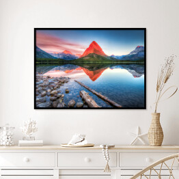 Plakat w ramie Czerwona góra i jej lustrzane odbicie w jeziorze - widok z brzegu usłanego kamieniami