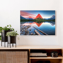Obraz na płótnie Czerwona góra i jej lustrzane odbicie w jeziorze - widok z brzegu usłanego kamieniami