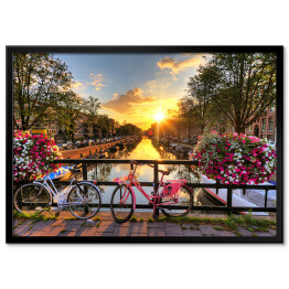 Plakat w ramie Most z rowerami i kwiatami na tle pięknego wschodu słońca, Amsterdam, Holandia